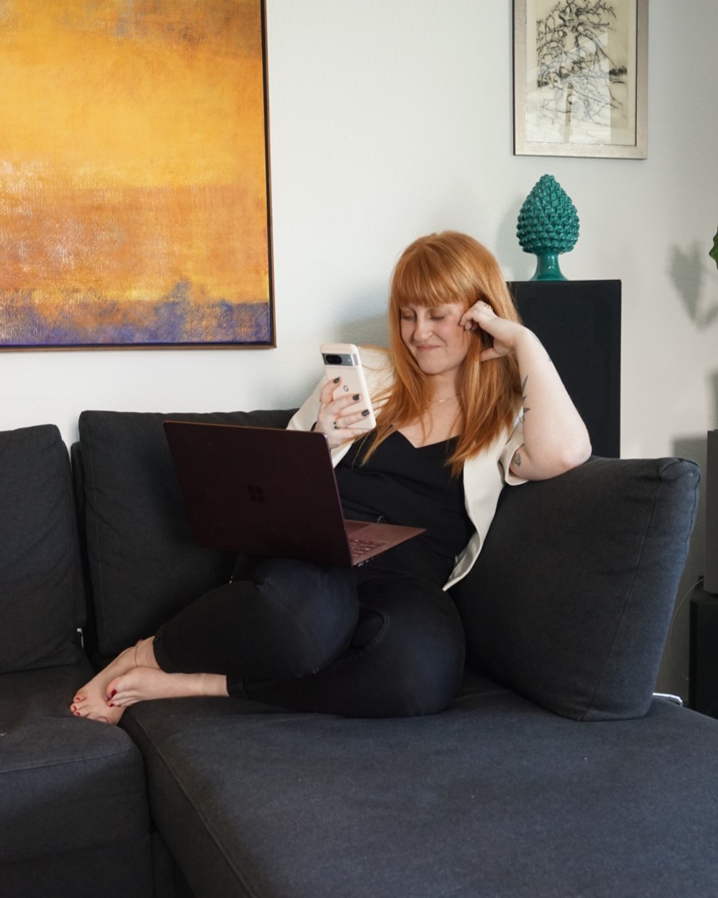 Une jeune femme rousse assise sur un tabouret portant un ordinateur portable, Mathilda, coach en marketing Digital et Human Design